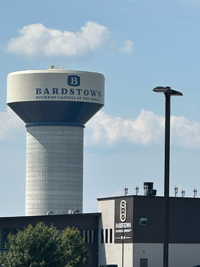 The iconic Bardstown water tower, labeled 'Bourbon Capital of the World,' overlooking the Bardstown Bourbon Company distillery.